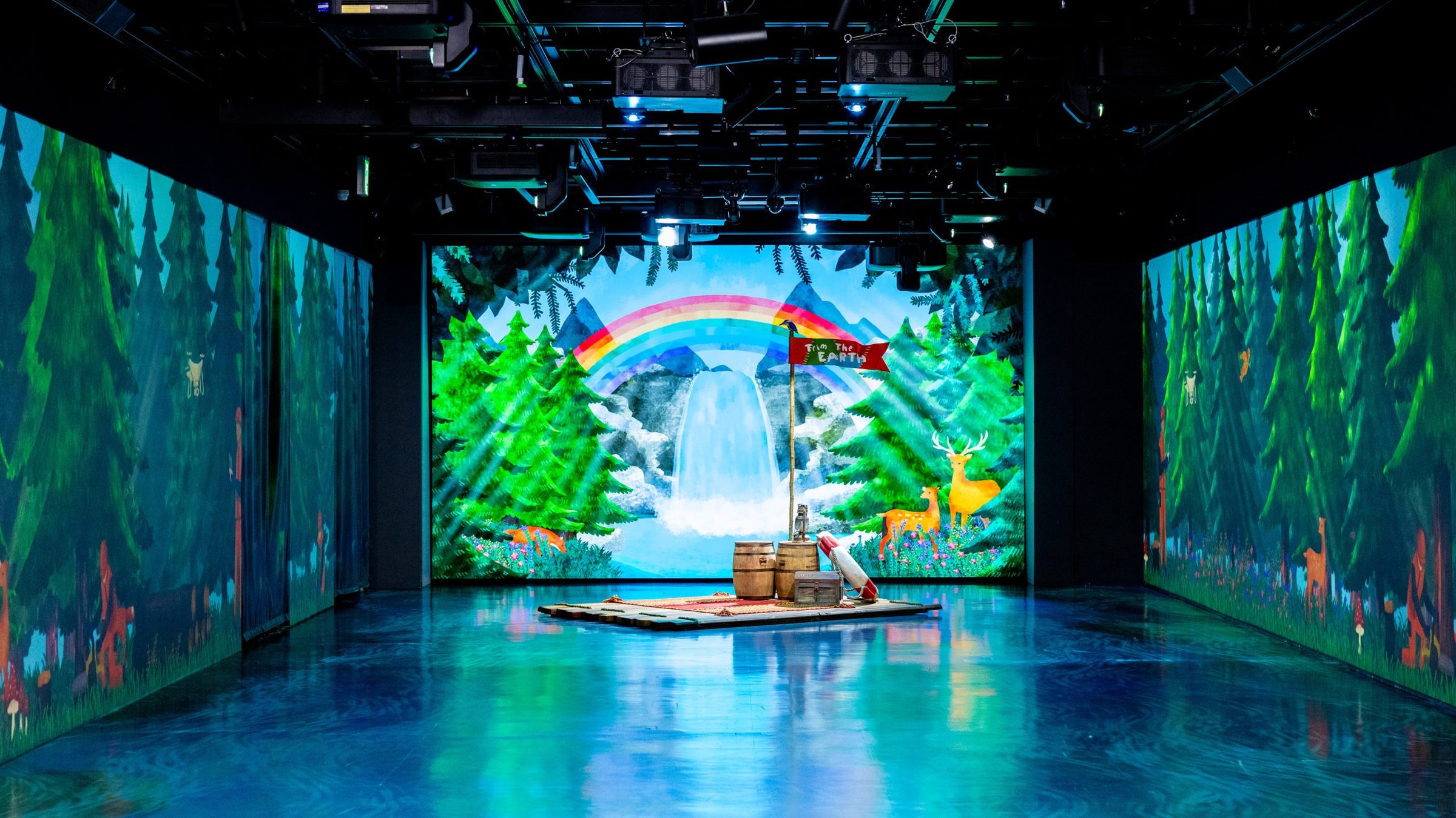 A room surrounded by forest visuals with a rainbow and waterfall